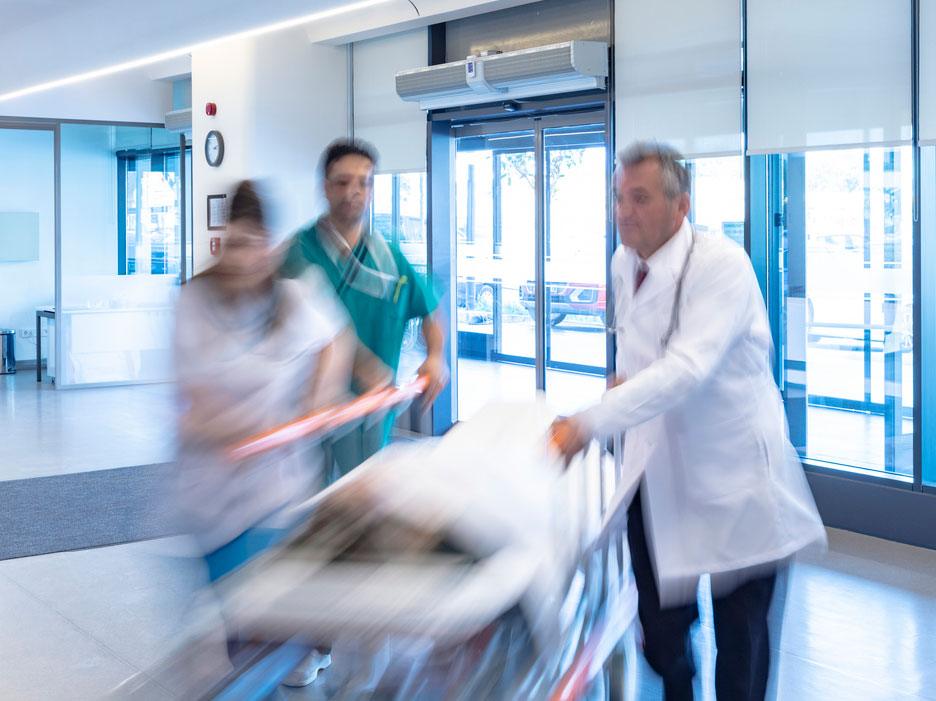 Medical professionals rushing person on gurney through building