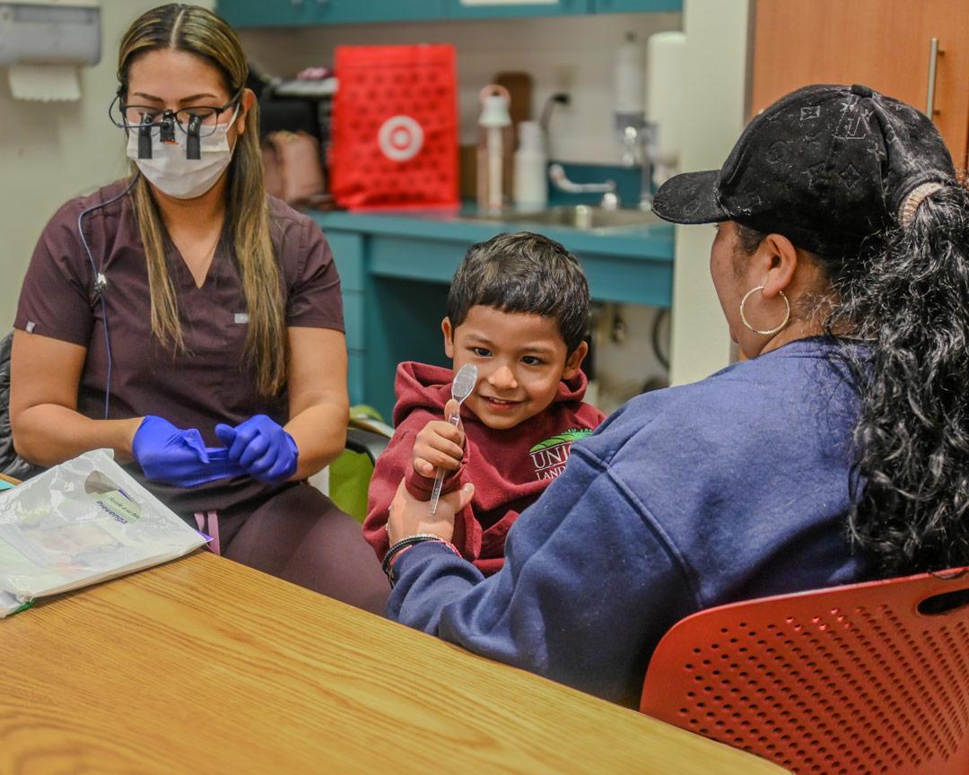 Child sitting with mother and medical professional at appointment