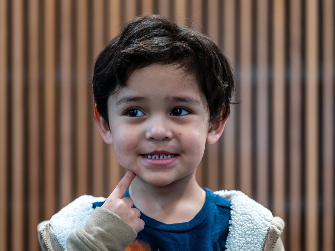 Child touching cheek looking off camera