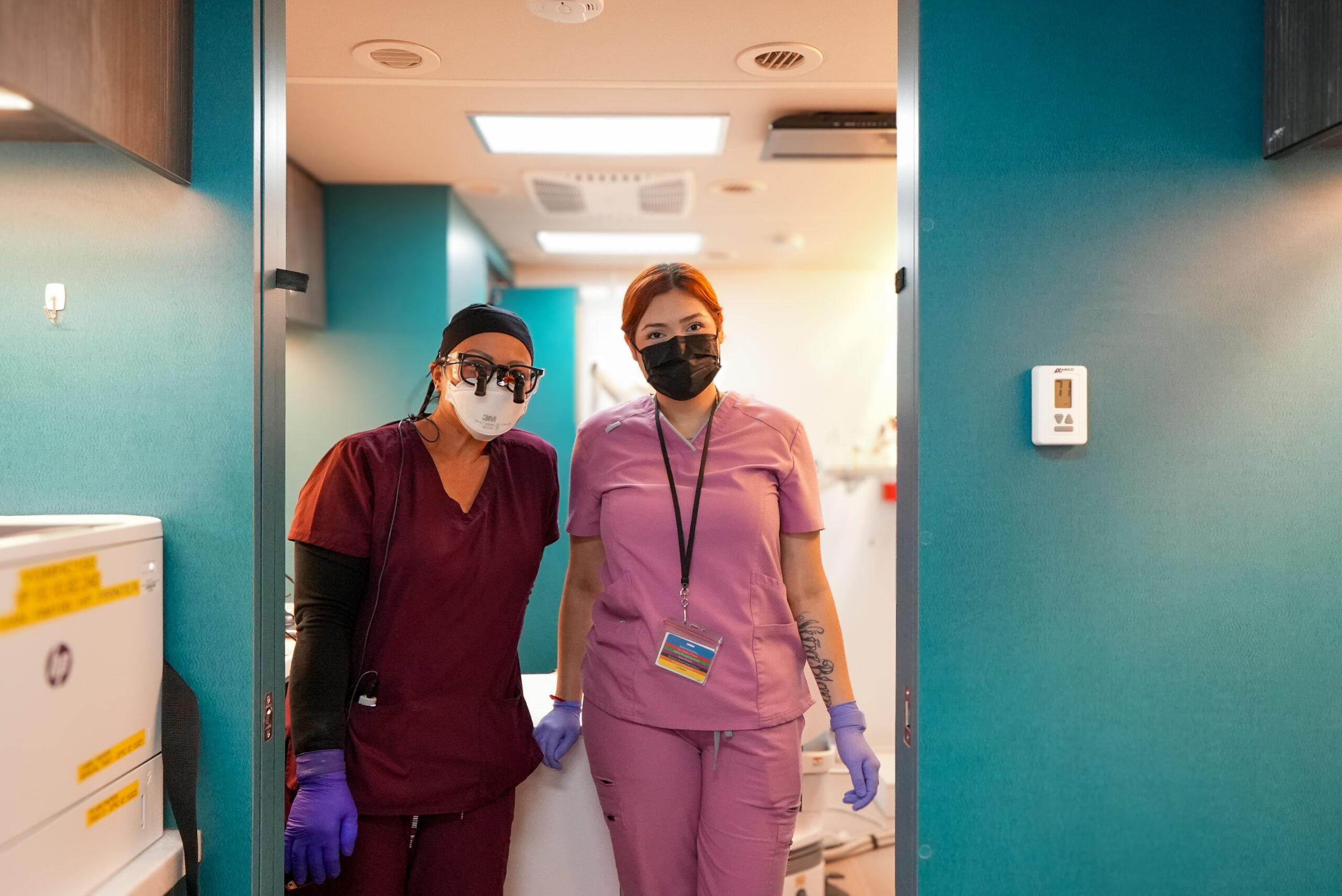 Dos profesionales de la medicina con mascarillas en la puerta sonriendo