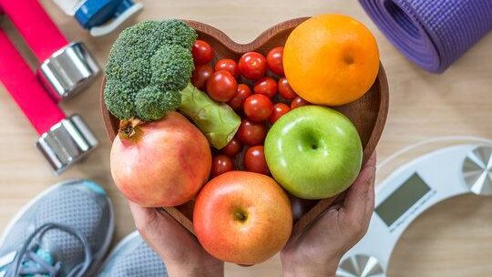 Tomando Control de Su Salud Healthy lifestyle concept, eating clean food good health dietary in heart dish with sporty gym aerobic body exercise workout training class equipment, weight scale and sports shoes in fitness center