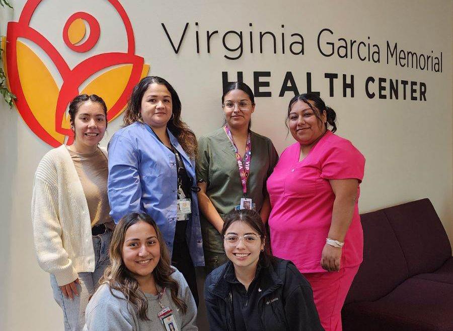Group of medical professionals smiling in front of a Virginia Garcia wall