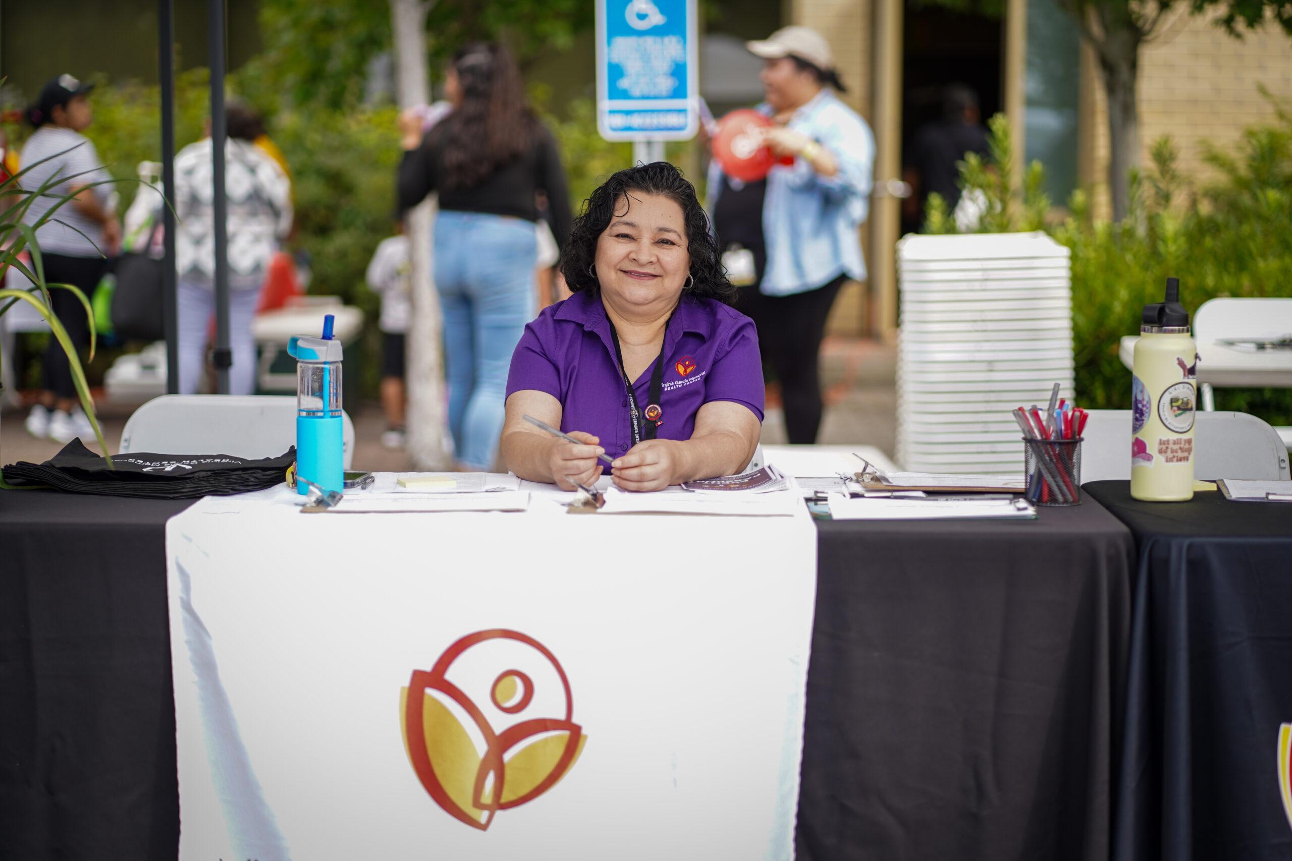 Woman smiling behind a booth with the Virginia Garcia logo