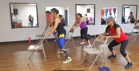 Group of people exercising with chairs.