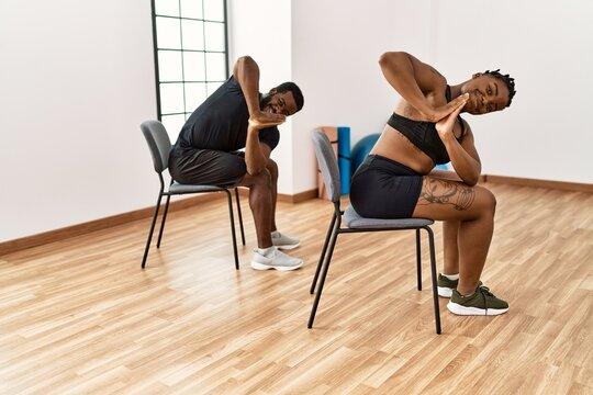 Young-couple-training-using-chair-at-sport-center